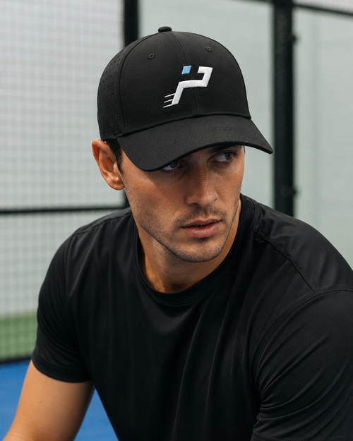 Casquette Technique Airflow noire Impulse Padel portée de face sur terrain de padel