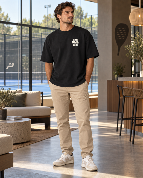 T-shirt homme oversize Impulse noir porté de face avec chino beige café dans un club de padel