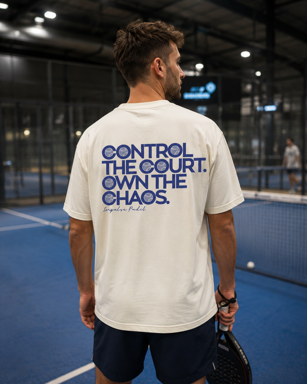 T-shirt Own The Chaos Impulse Padel porté de dos sur terrain de padel