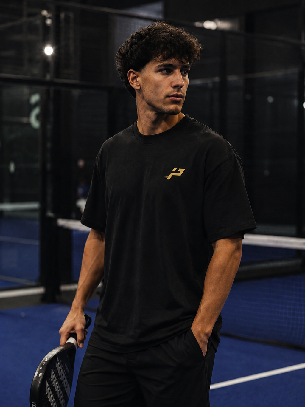 T-shirt Play Hard Feel Free noir et or porté de face sur terrain de padel