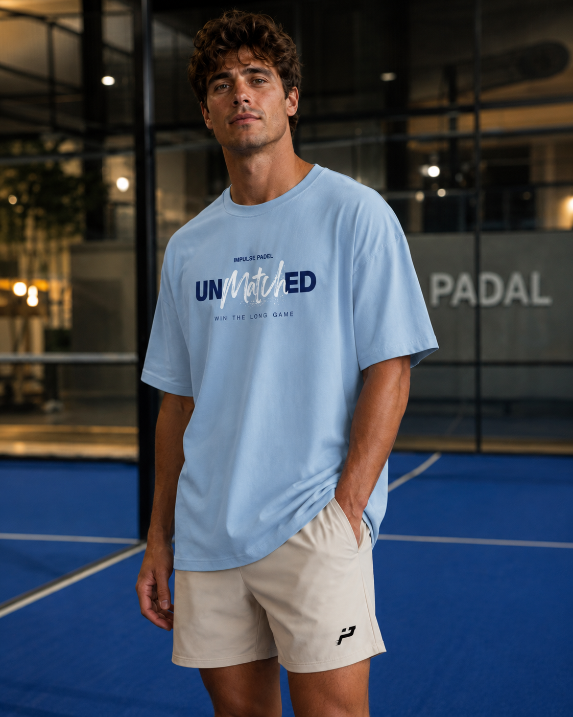 T-shirt Unmatched bleu Impulse Padel porté de face sur terrain de padel